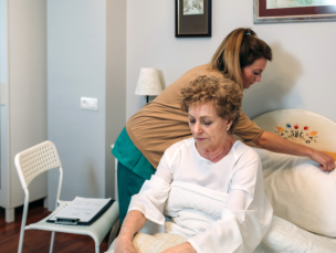 aide arranging the bed for the senior woman