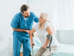 aide assisting the senior woman to stand