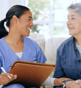 aide smiling and senior woman looking at each other