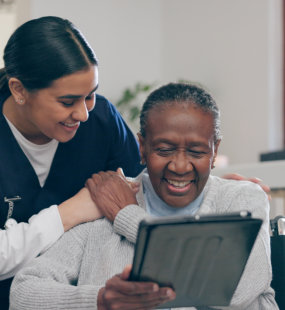 aide assisting the senior woman on her phone