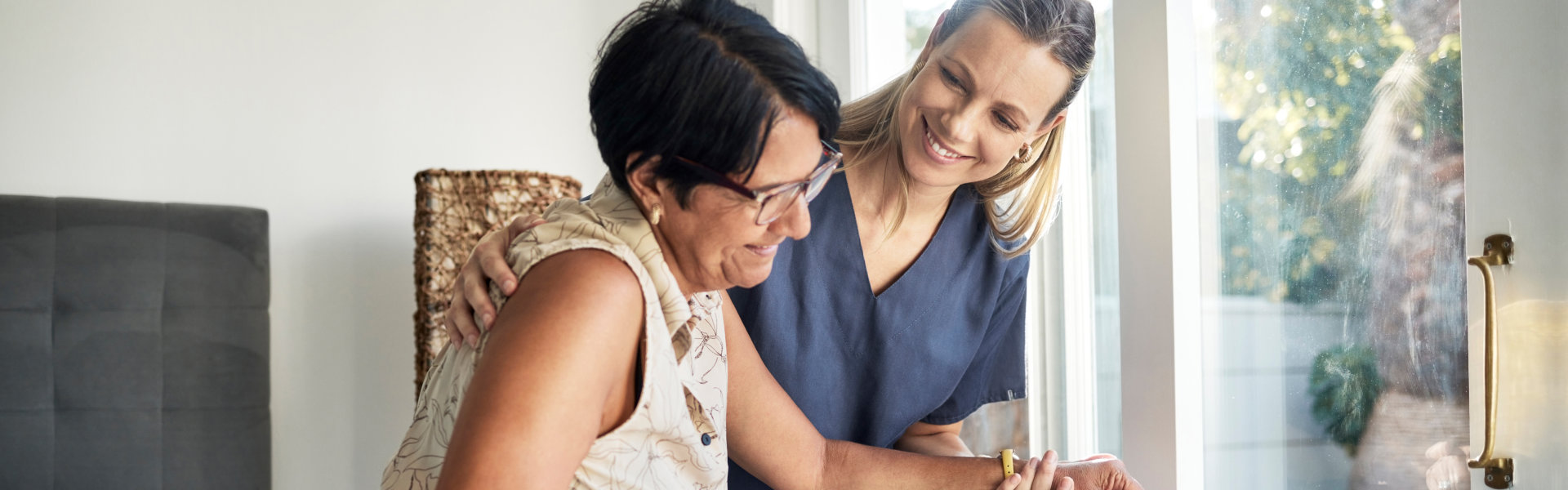 aide smiling while taking care of the senior woman