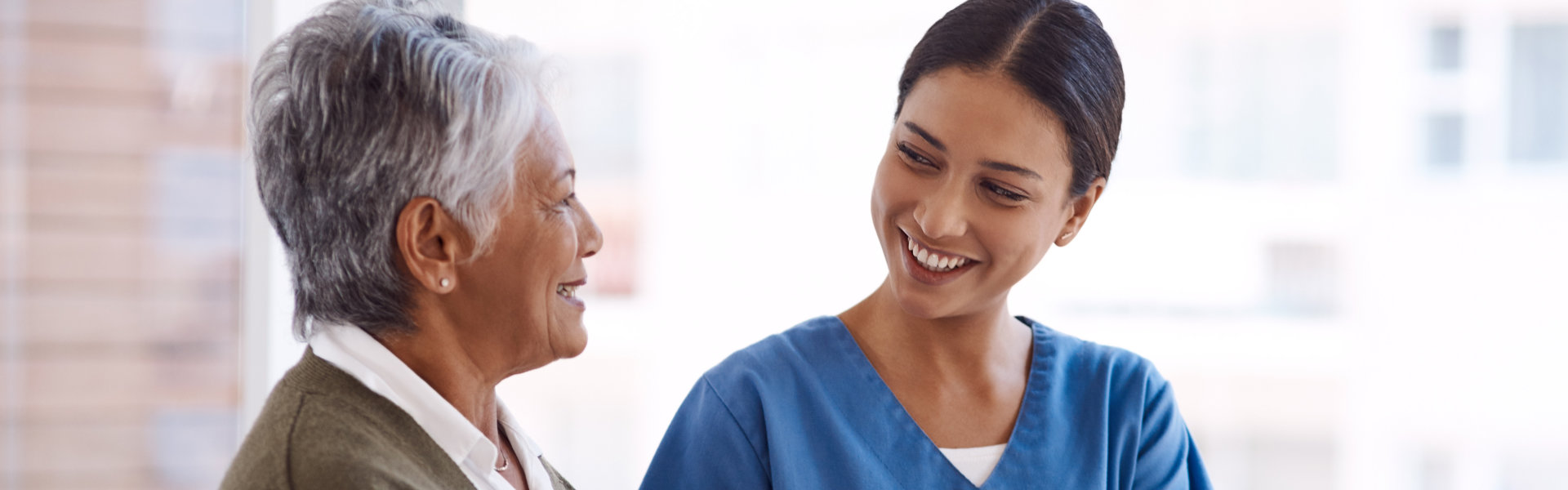 aide and senior woman smiling together