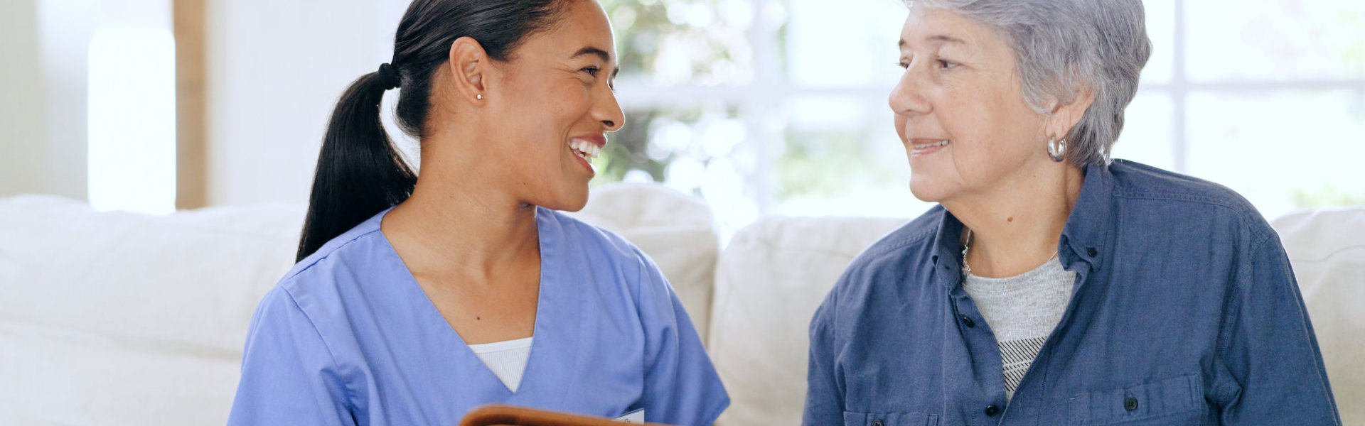aide smiling and senior woman looking at each other